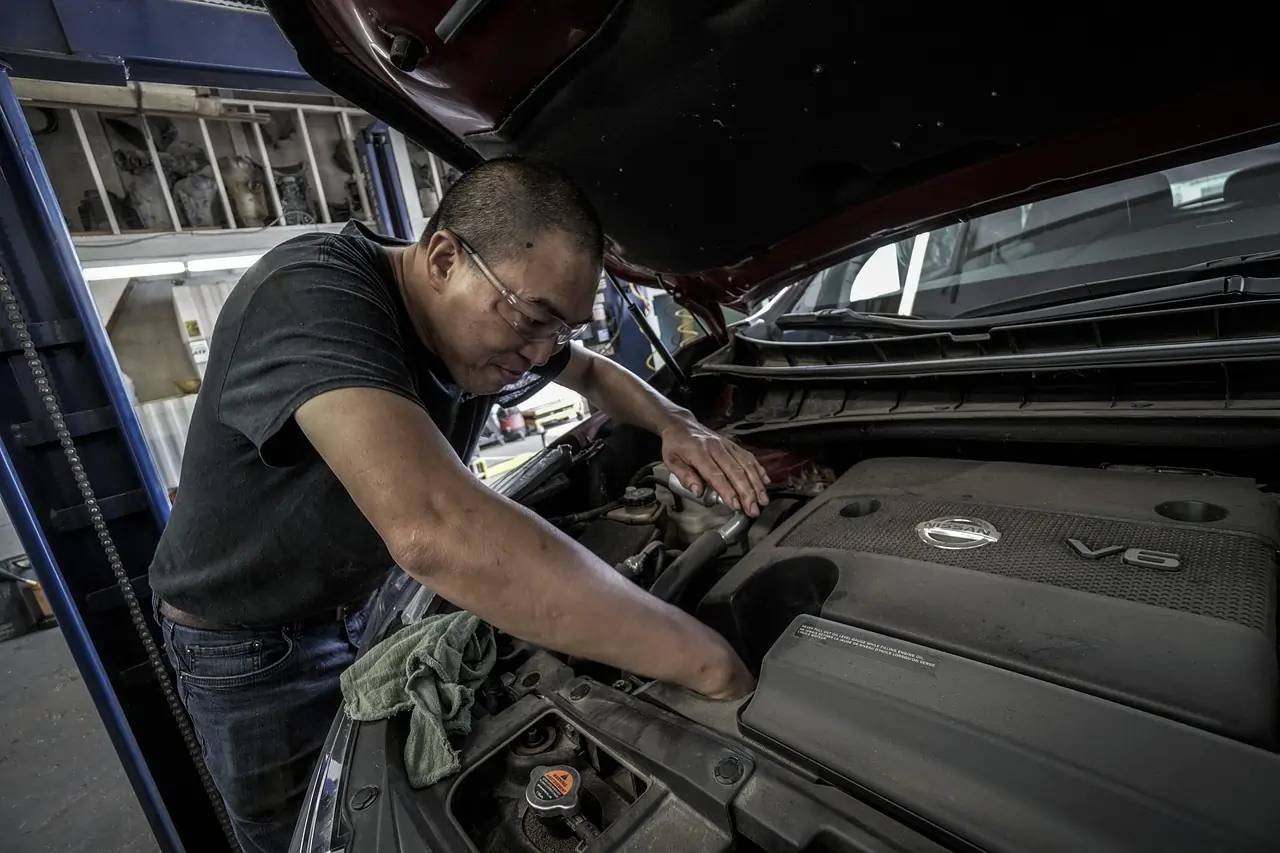 Mécanicien professionnel réparant une voiture dans un garage à Vigneux-sur-Seine, utilisant des outils spécialisés sous un éclairage industriel.
