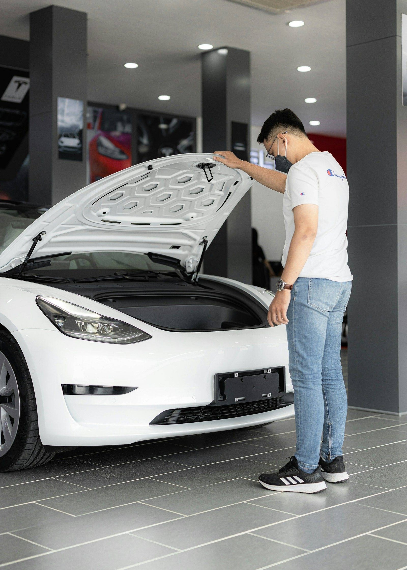 Homme inspectant le moteur d'une voiture d'occasion capot ouvert avant l'achat