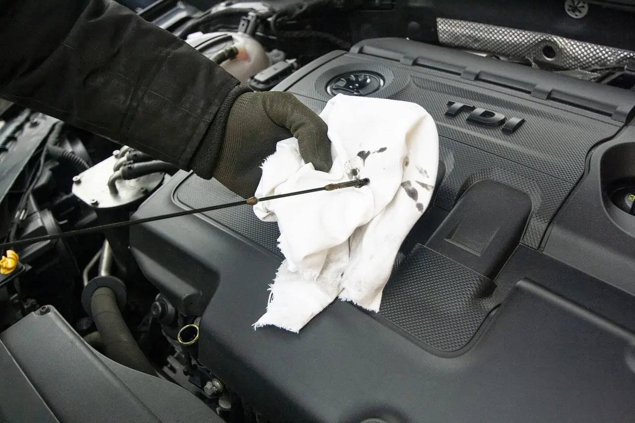 Mécanicien vérifiant le niveau d'huile moteur pendant l'entretien périodique d'une voiture chez GH Car à Vigneux-sur-Seine