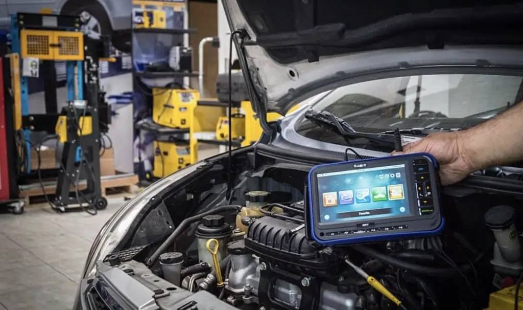 Diagnostic électronique automobile à Vigneux-sur-Seine, mécanicien expert utilisant des outils modernes pour analyser les systèmes électroniques du véhicule dans un garage professionnel.