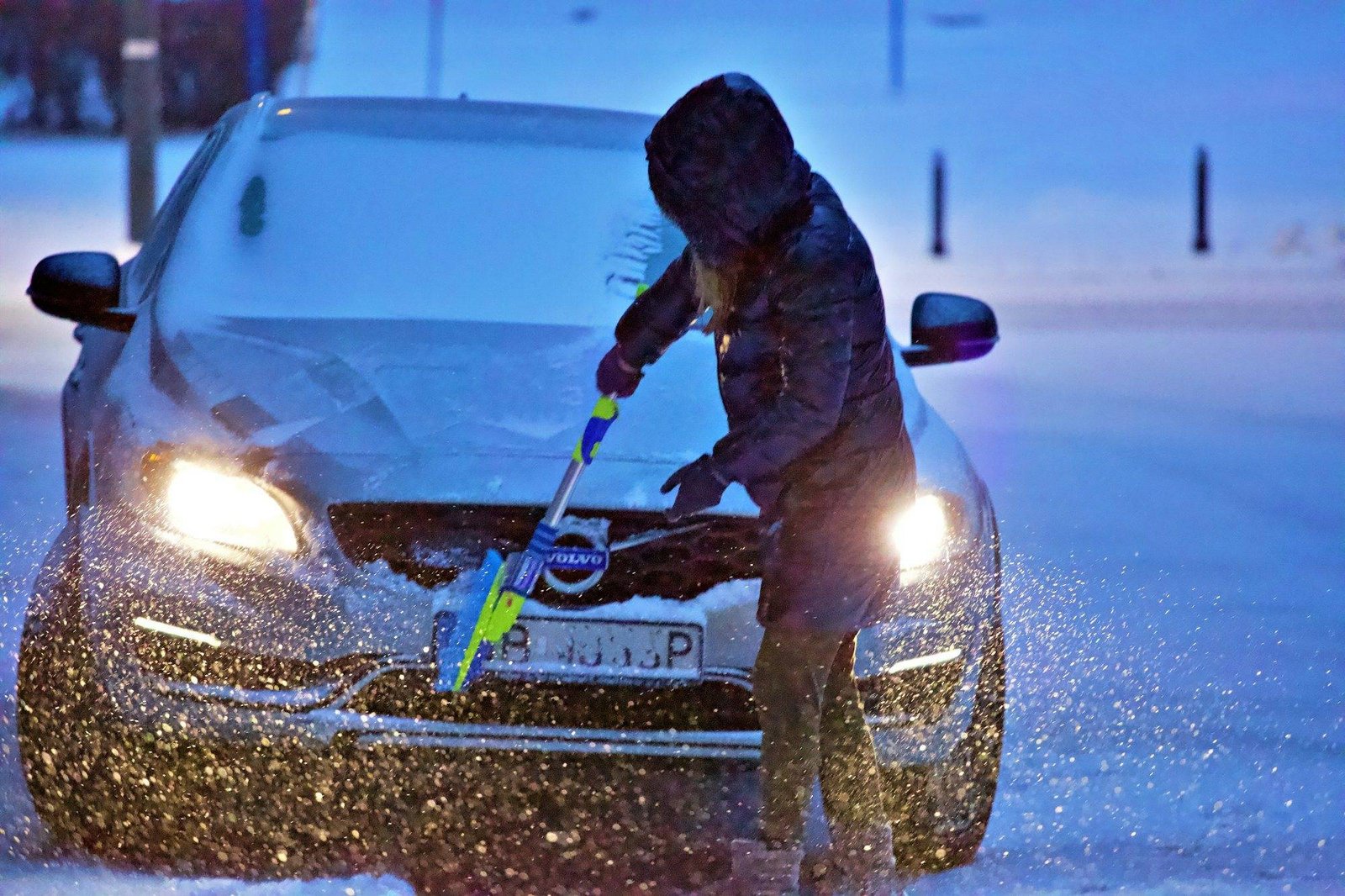 Conducteur dégivrant le pare-brise d'une voiture enneigée, préparer sa voiture pour l'hiver